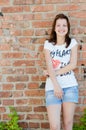 Young happy teen girl standing at brick wall background copyspace Royalty Free Stock Photo