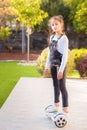 Young happy teenager girl balancing on electric hoverboard at the sunny park, sunny day. Side view.