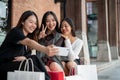 Young happy three Asian female friends are taking selfies with a phone after shopping in the city Royalty Free Stock Photo