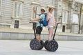 Young happy tourist couple riding segway enjoying city tour in Madrid palace in Spain having fun driving together