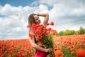 Young happy ukrainian woman holding bouquet of poppies flowers walking, enjoy sunny day in field Royalty Free Stock Photo