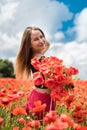 Young happy ukrainian woman holding bouquet of poppies flowers walking, enjoy sunny day in field Royalty Free Stock Photo