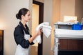 A young happy uniformed maid carrying towels