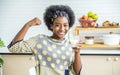 Young happy woman african american afro hair making strong hand while drinking a milk for breakfast with fun