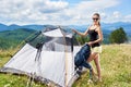 Woman tourist hiking in mountain trail, enjoying summer sunny morning in mountains near tent Royalty Free Stock Photo