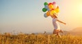 Happy woman with balloons at sunset in summer