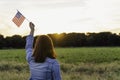 Young happy woman from behind with the United States flag enjoying sunset in nature. 4th of july independence day of the united Royalty Free Stock Photo