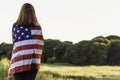 Young happy woman from behind with the United States flag enjoying sunset in nature. 4th of july independence day of the united Royalty Free Stock Photo