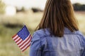 Young happy woman from behind with the United States flag enjoying sunset in nature. 4th of july independence day of the united Royalty Free Stock Photo