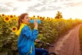 Young happy woman bicyclist drinking water after riding bicycle in sunflower field. Summer sport activity Royalty Free Stock Photo