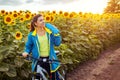 Young happy woman bicyclist drinking water after riding bicycle in sunflower field. Summer sport bike activity Royalty Free Stock Photo