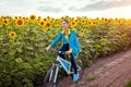 Young happy woman bicyclist riding bicycle in sunflower field. Summer sport activity. Healthy lifestyle Royalty Free Stock Photo