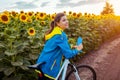 Young happy woman bicyclist riding bicycle in sunflower field. Summer sport activity. Healthy lifestyle Royalty Free Stock Photo