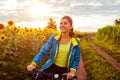 Young happy woman bicyclist riding bicycle in sunflower field. Summer sport activity. Healthy lifestyle Royalty Free Stock Photo