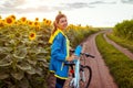 Young happy woman bicyclist riding bicycle in sunflower field. Summer sport activity. Healthy lifestyle Royalty Free Stock Photo