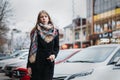 Young happy woman blonde in a black coat and scarf walks through city. Waiting for meeting Royalty Free Stock Photo