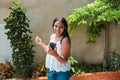 Young and happy woman with casual clothes and smartphone in hand, having fun and dancing while resting at home