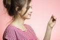 Young happy woman with checking result of a one-time pregnancy test, family planning, motherhood concept on pink studio background