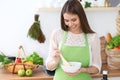 Young happy woman is cooking or eating fresh salad in the kitchen. Food and health concept Royalty Free Stock Photo