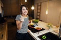 Young happy woman cooking a healthy meal in home kitchen.Making dinner on kitchen island standing by induction hob.Preparing fresh Royalty Free Stock Photo