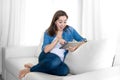 Young happy woman on couch at home enjoying using digital tablet computer Royalty Free Stock Photo