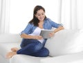 Young happy woman on couch at home enjoying using digital tablet computer Royalty Free Stock Photo