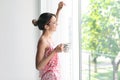 Young happy woman with cup of aromatic coffee near window at home Royalty Free Stock Photo
