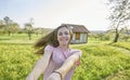 Young happy woman, dancing around in German countryside in the background grasslands, trees and a half-timbered house