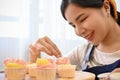 Happy woman decorating her fresh baked homemade cupcake in the kitchen, hobby, free time Royalty Free Stock Photo