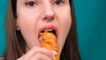 Young happy woman eating deep fried chicken, closeup. Woman eats chicken wings, calorie intake and health risks