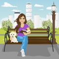 Young happy woman enjoying freetime in city park in summer reading book sitting on a bench hugging labrador puppy Royalty Free Stock Photo