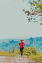 Young happy woman enjoying in a healthy lifestyle while jogging on a country road through the beautiful sunny forest Royalty Free Stock Photo