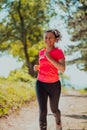 Young happy woman enjoying in a healthy lifestyle while jogging on a country road through the beautiful sunny forest Royalty Free Stock Photo