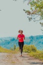 Young happy woman enjoying in a healthy lifestyle while jogging on a country road through the beautiful sunny forest Royalty Free Stock Photo