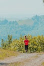 Young happy woman enjoying in a healthy lifestyle while jogging on a country road through the beautiful sunny forest Royalty Free Stock Photo
