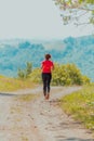 Young happy woman enjoying in a healthy lifestyle while jogging on a country road through the beautiful sunny forest Royalty Free Stock Photo