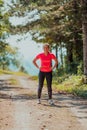 Young happy woman enjoying in a healthy lifestyle while jogging on a country road through the beautiful sunny forest Royalty Free Stock Photo