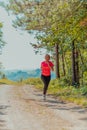 Young happy woman enjoying in a healthy lifestyle while jogging on a country road through the beautiful sunny forest Royalty Free Stock Photo