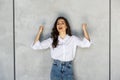 Young happy woman exults pumping fists ecstatic celebrates success isolated on gray wall background Royalty Free Stock Photo