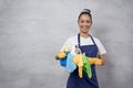 Young happy woman, female cleaner in uniform and rubber gloves holding bucket of cleaning supplies and smiling at camera Royalty Free Stock Photo