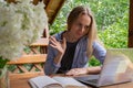 Young happy woman focuses on her laptop in wooden alcove. Relaxed outdoor setting emphasizes comfort and productivity Royalty Free Stock Photo