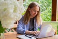 Young happy woman focuses on her laptop in wooden alcove. Relaxed outdoor setting emphasizes comfort and productivity Royalty Free Stock Photo