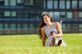 Young happy woman on grass looking away holding mobile phone