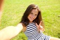 Young happy woman on grass taking selfie
