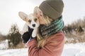 Young happy woman having fun in snowy winter park with Corgi baby dog Royalty Free Stock Photo