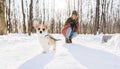 Young happy woman having fun in snowy winter park with Corgi baby dog Royalty Free Stock Photo