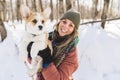 Young happy woman having fun in snowy winter park with Corgi baby dog Royalty Free Stock Photo