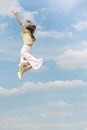 Young happy woman with her hands raised up during jump against the blue sky. Young girl flying high in blue sky Royalty Free Stock Photo