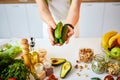 Young happy woman holding cucumbers for making salad in the beautiful kitchen with green fresh ingredients indoors. Healthy food Royalty Free Stock Photo