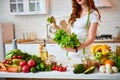 Young happy woman holding lettuce leaves for making salad in the beautiful kitchen with green fresh ingredients indoors. Healthy Royalty Free Stock Photo